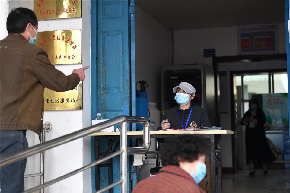 3月23日,武汉市青山区青山镇街石化社区,社区工作人员在为居民办理出入证明。