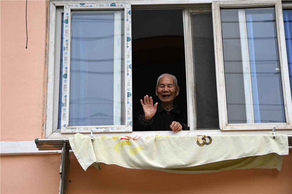3月23日,武汉市青山区青山镇街船厂社区,一位爹爹在自家窗口和网格员打招呼。