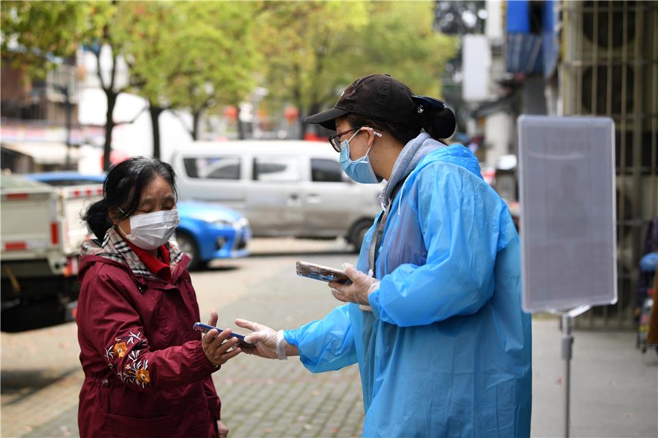 3月23日,武汉市青山区青山镇街船厂社区中百超市,店员在指导老年居民使用健康码。