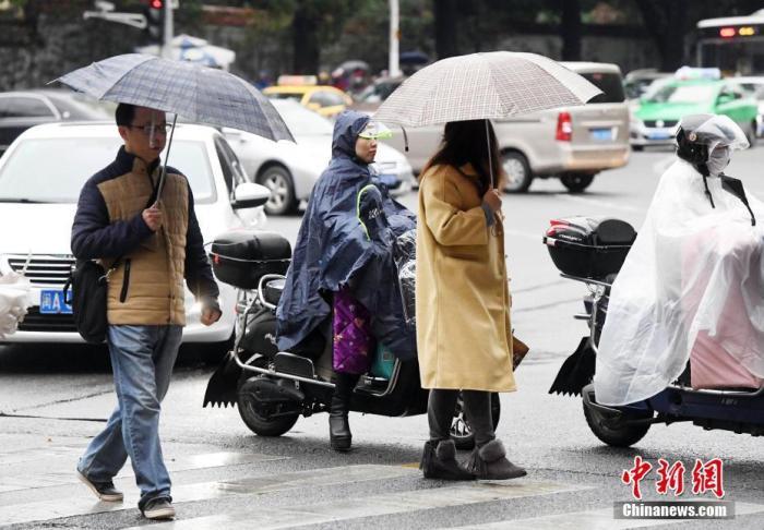资料图:市民冒雨出行。 中新社记者 刘可耕 摄