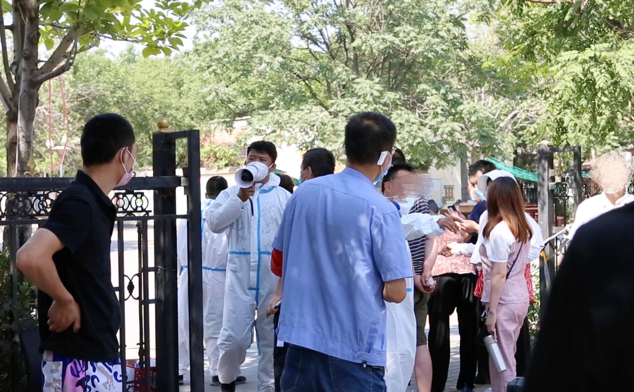 6月16日下午,卢沟桥街道青塔街心公园核酸检测点外,街道办工作人员在维持秩序。新京报见习记者 赵敏 摄