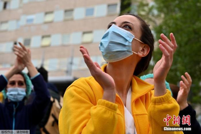 资料图:当地时间4月27日,在西班牙马德里的一家医院外,医护人员在为全国禁闭期间居家隔离的民众们鼓掌欢呼,为他们加油打气。