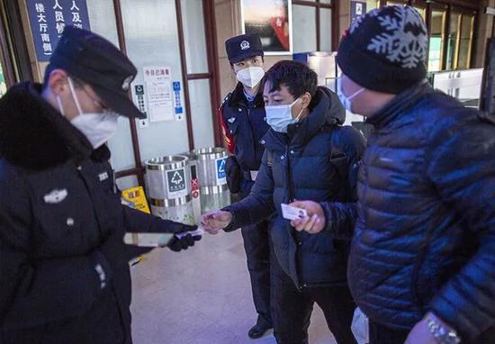 ▲1月28日23时36分,北京站进站大厅门口,执勤民警核验旅客身份证。民警李佳梦(左二)仔细观察身边旅客。